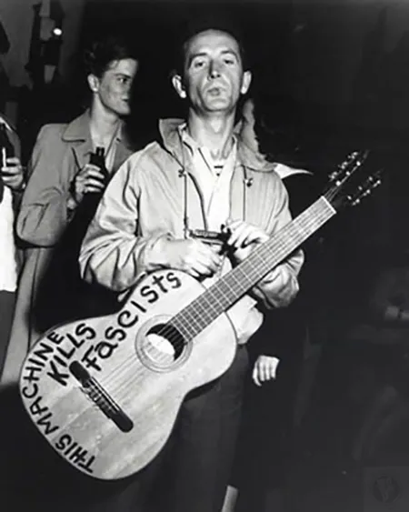 Woody with his iconic Gibson guitar featuring hand painted sign: This Machine Kills Fascists